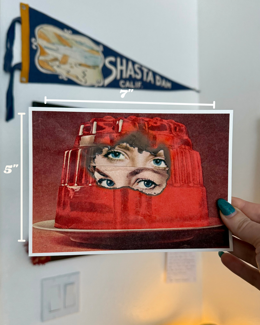Red jelly mold with face design held by a hand, with a Shasta Dam banner in the background.