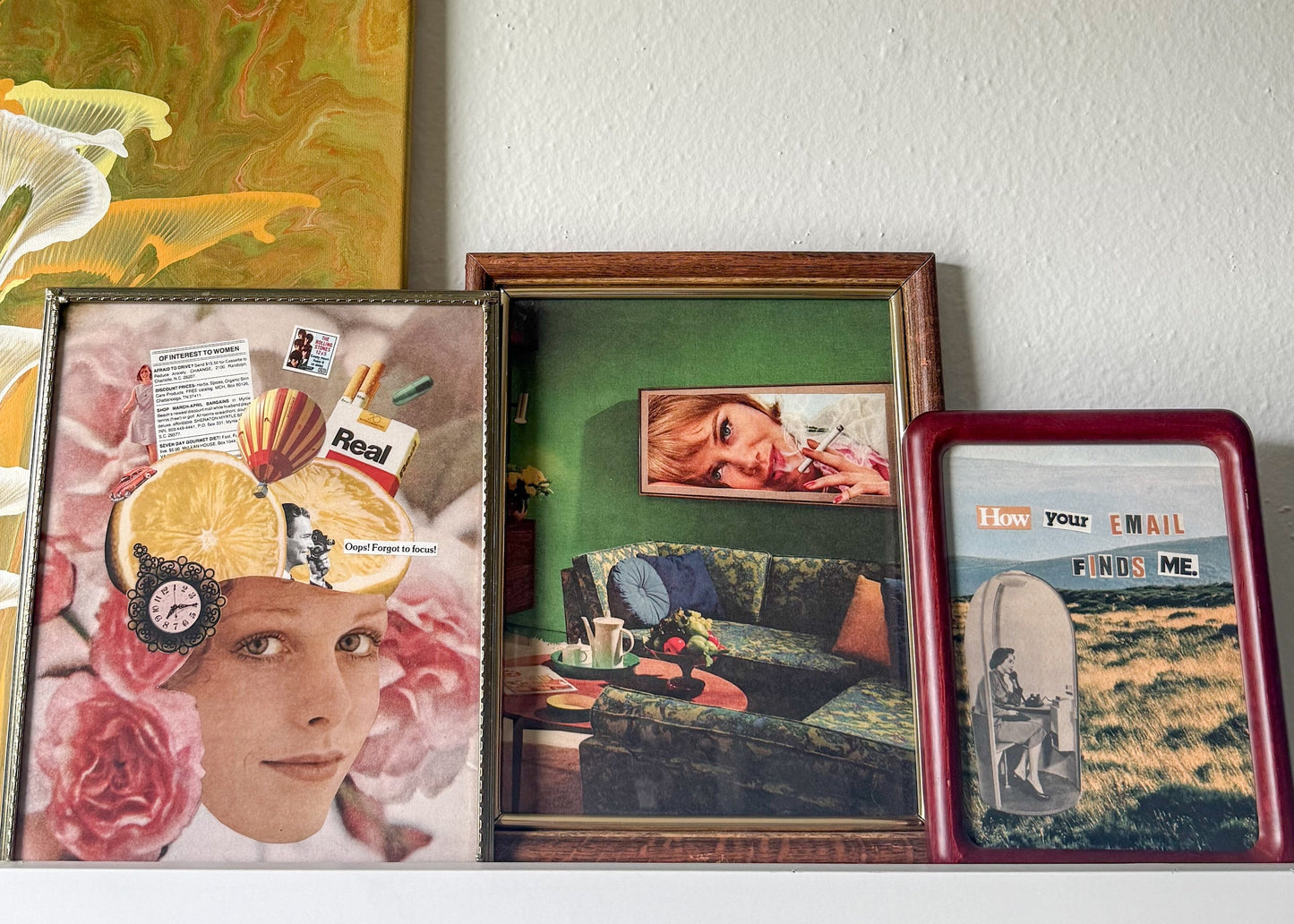 Three framed vintage-style collage prints displayed side-by-side on a white shelf against a textured white wall.