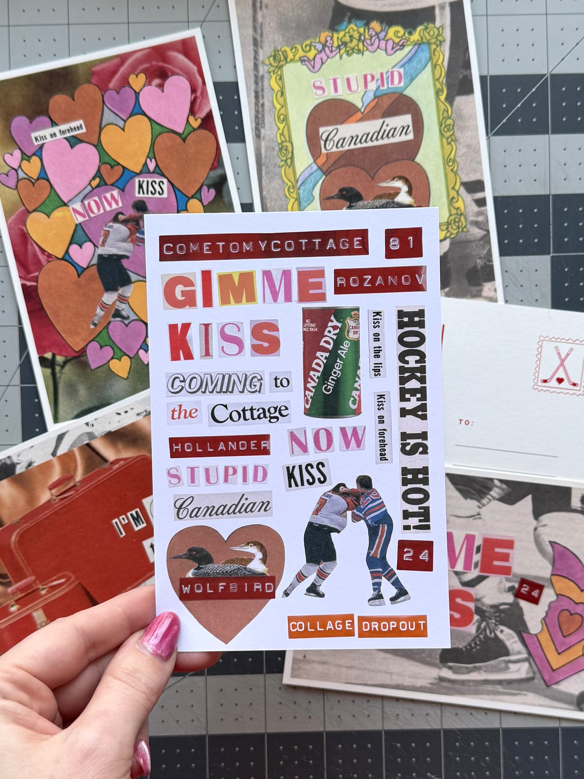 Hand holding the bonus sheet of DIY collage words, a loon, and hockey players