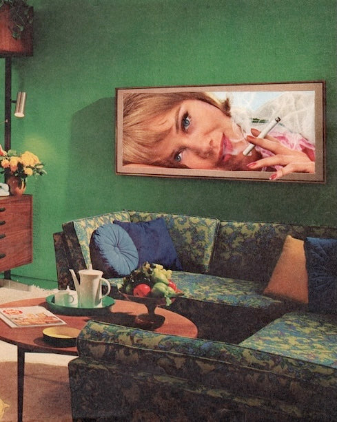 Living room with a green wall, floral-patterned sofa, and framed picture of a woman smoking a cigarette.